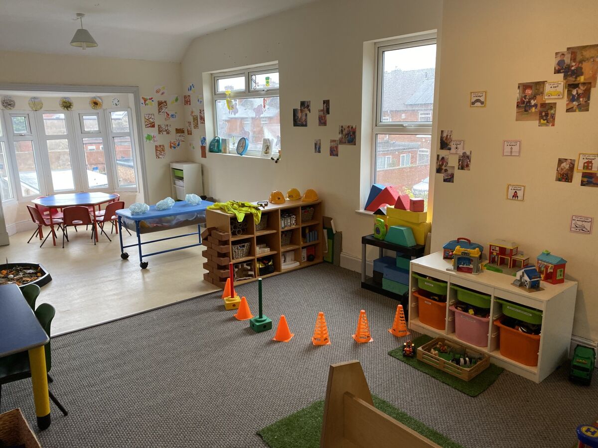 A spacious room with a home corner, building blocks and an obstacle course